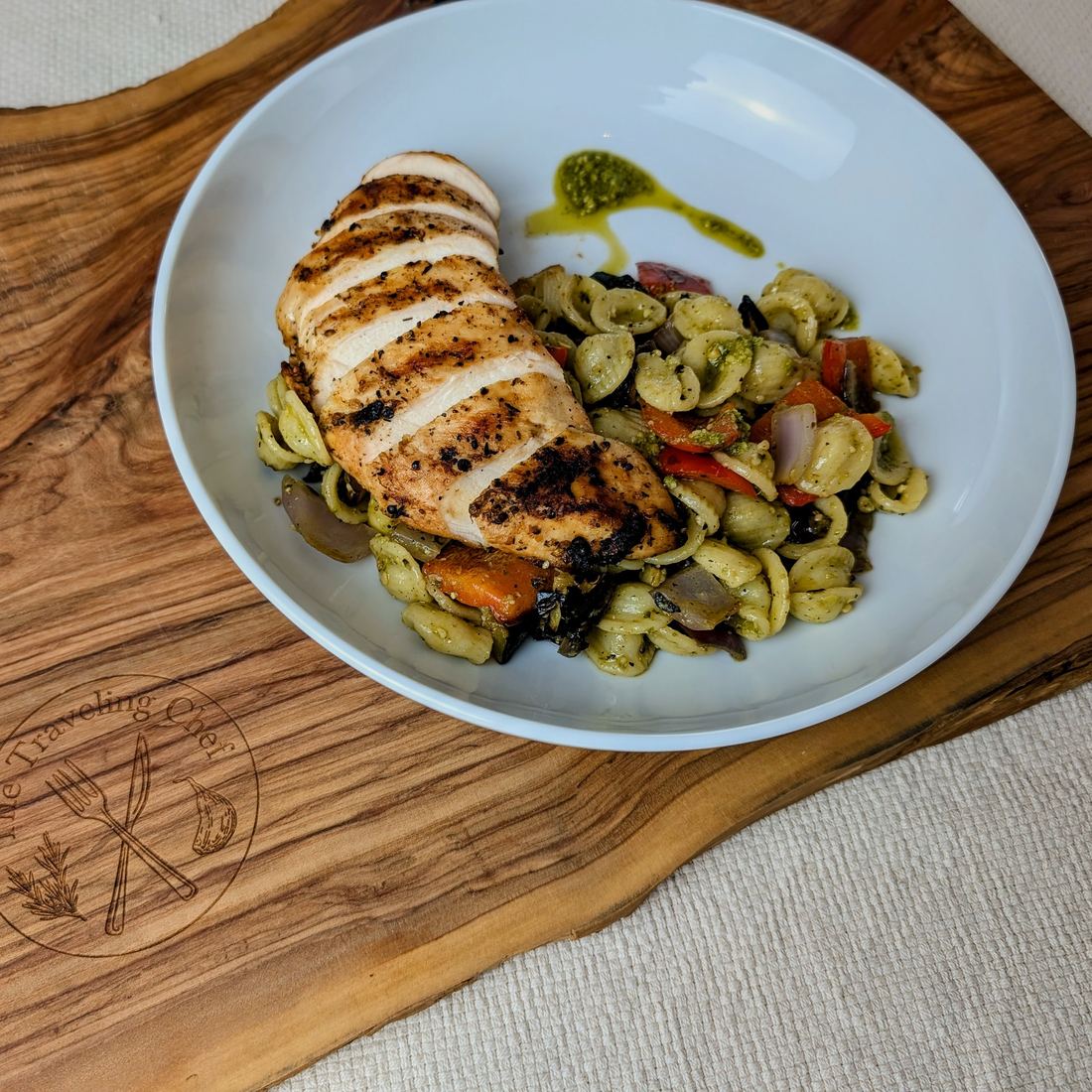 Grilled chicken over orzo salad on olive-wood board